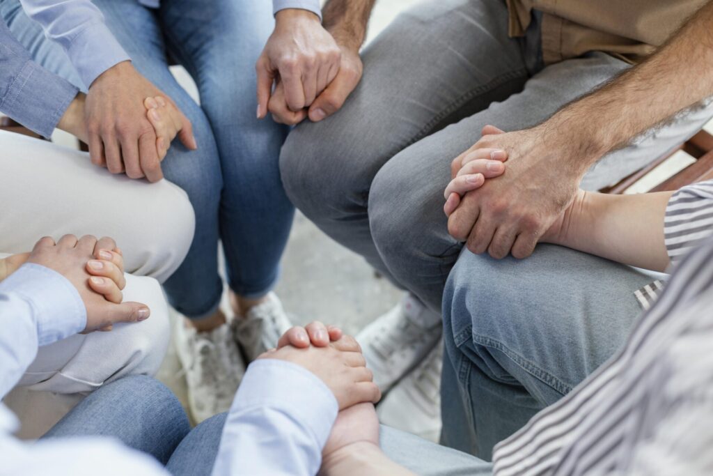 Personnes en ronds se tenant la main, renforçant la cohésion familiale suite à une séance de thérapie familiale à Narbonne